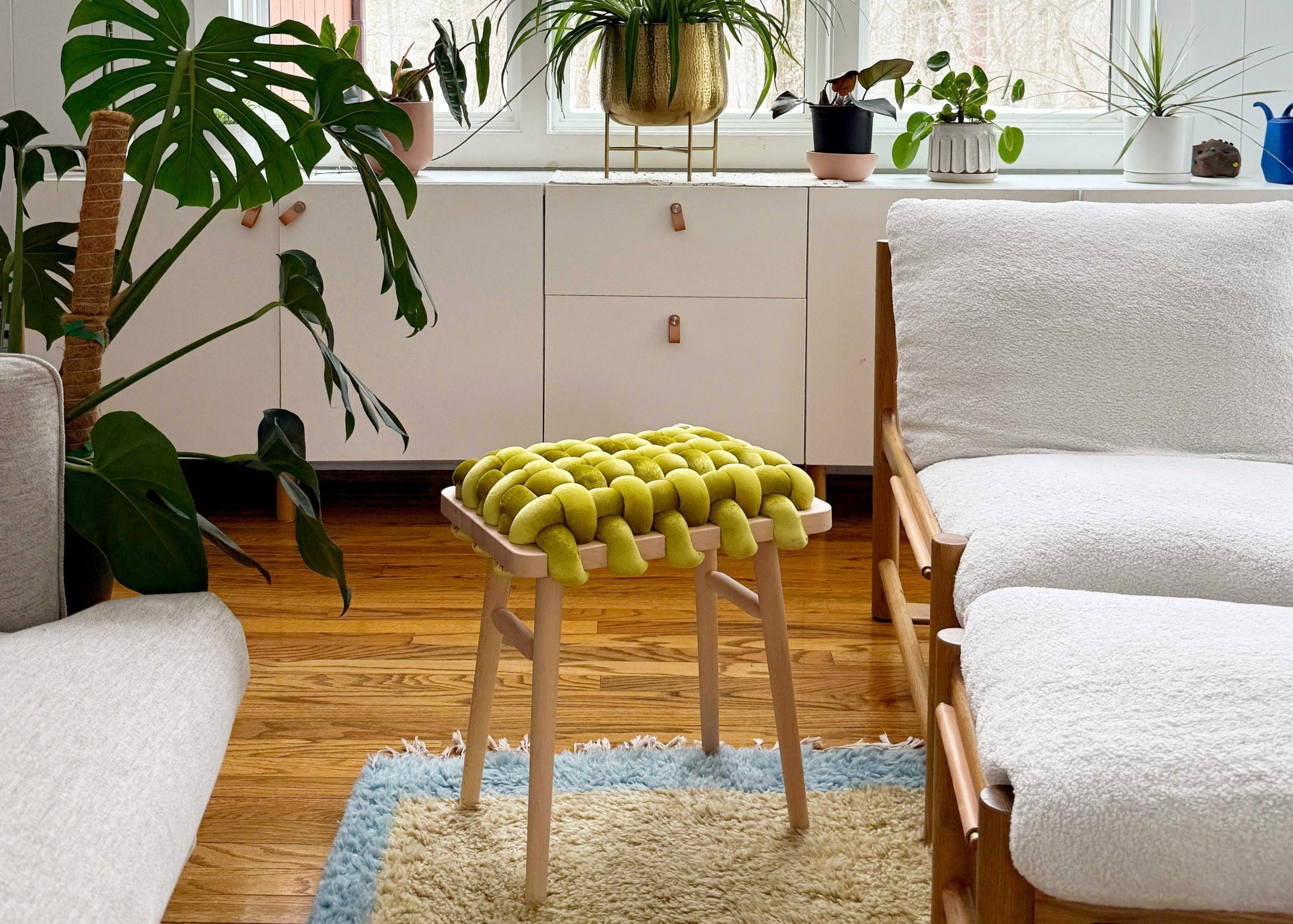 Modern living room with white furniture, plants, and a large window.